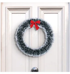 Detailed view of white and green tinsel Christmas wreath with a red bow on a white door