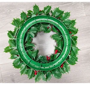 Back view of Christmas holly wreath featuring green plastic frame and red berries