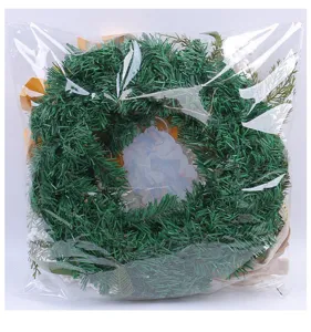 Christmas wreath with gold oil lamp and white berries in clear plastic product packaging.