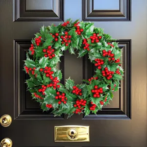 Festive Christmas wreath featuring green leaves and vibrant red berries on a black front door