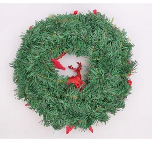 Detailed view of an artificial Christmas pine needle wreath with red reindeer and berries.