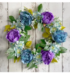 Detailed view of artificial purple and blue peony wreath on white rustic wood background.