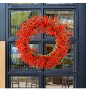Levendige rode kunstbloemen krans aan een zwarte glazen deur voor tuin decoratie