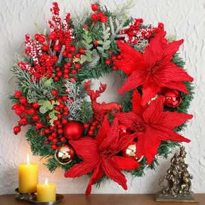 Festive Christmas wreath with red poinsettias, berries, and a deer figurine on white wall.