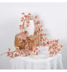 Viti di foglie di patata dolce artificiali su ceppo di legno per decorazioni autunnali.