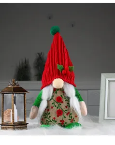Detail view of a handmade Christmas gnome plush with red knitted hat and floral pattern