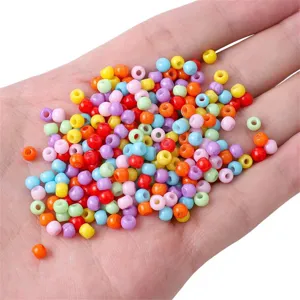 Vibrant 4mm oil-painted glass seed beads held in hand for DIY jewelry making projects