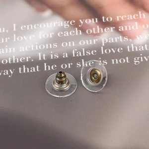 Close-up of clear plastic and bronze metal earring backs for DIY jewelry making.