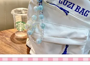 Dettaglio di un ciondolo per borsa con fiocco di perline blu cangianti su uno zaino