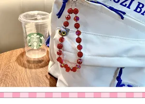 Gros plan d'un bijou de sac à perles rouges avec tête de chat sur un sac blanc