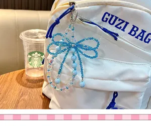 Detailansicht eines funkelnden blauen Kristallperlen-Anhängers am weißen Rucksack