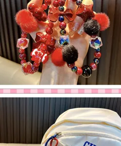 Detailopname van een rode kralen telefoonkoord met pompons en een strikje