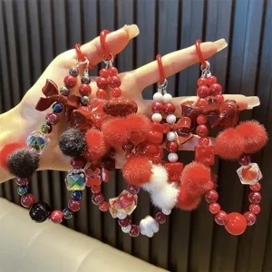 Rode kralen telefoonkoord met pluizige pompons en schattige strikjes als bedeltjes