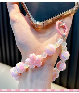 Vue détaillée de la lanière de téléphone perlée en fleurs de cerisier rose sur le poignet