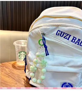 Détail d'un charme de sac en perles de fleurs lumineuses sur un sac à dos en toile blanche