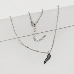 Close-up view of a stainless steel necklace featuring a black chili cornicello lucky pendant