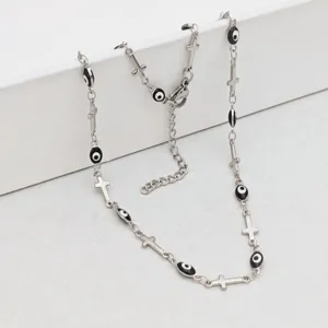 Detailed view of stainless steel cross necklace featuring black and white evil eye beads