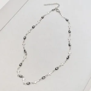 Close-up detail of stainless steel necklace with evil eye beads and cross charms