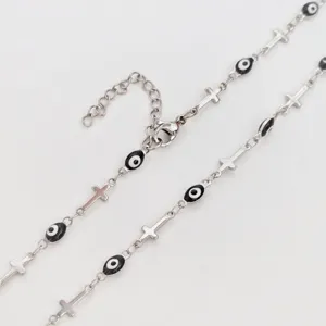 Detail view of silver stainless steel necklace with evil eye beads and cross charms.