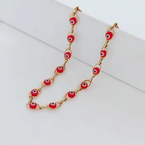 Macro shot of red glass evil eye beads detailed on a gold link stainless steel chain