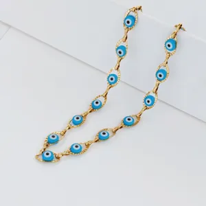 Close-up detail of golden stainless steel necklace with blue evil eye beads