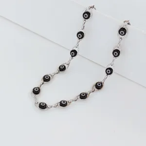Detail view of stainless steel necklace with multiple black evil eye beads on silver chain