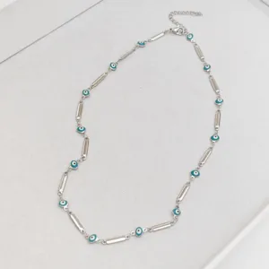 Detail view of a stainless steel evil eye necklace with blue enamel and silver links.