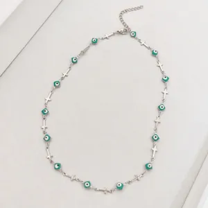 Close-up view of a stainless steel necklace with crosses and turquoise evil eye charms.
