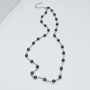Macro detailed view of silver stainless steel necklace with black evil eye bead stations.