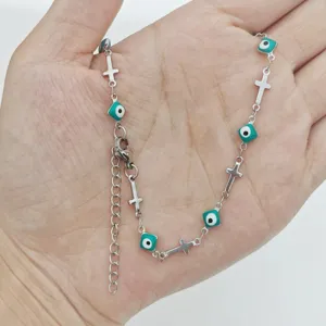 Detailed view of stainless steel cross necklace featuring teal evil eye enamel charms