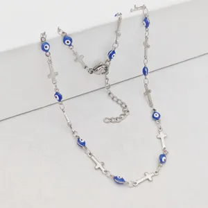 Detail shot of a silver stainless steel necklace with blue evil eye beads and small crosses.