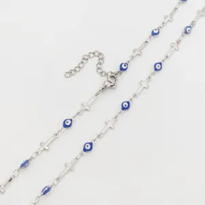 Close-up detail of a silver stainless steel cross necklace with blue evil eye enamel beads.