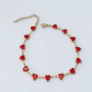 Detailed macro view of gold-toned stainless steel anklet featuring vibrant red heart stones