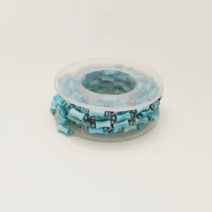 Close-up of light blue acrylic bamboo-shaped beads on a stainless steel chain roll.