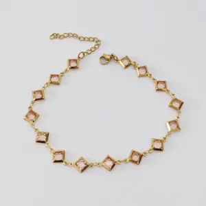 Detailansicht von rosa rautenförmigen Glassteinen an einer goldenen Edelstahl-Fußkette