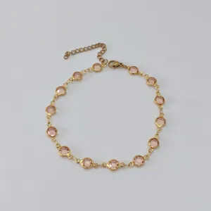Detailed macro view of a gold-plated stainless steel anklet with pink round crystals
