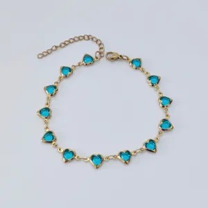 Detailed view of a gold-tone stainless steel anklet featuring bright blue heart gems.