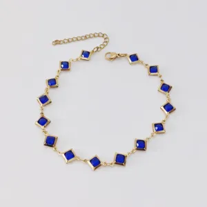 Detailansicht eines goldenen Edelstahl-Fußkettchens mit rhombenförmigen blauen Glassteinen