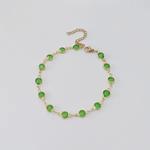 Detail of gold stainless steel anklet featuring vibrant green round glass charms