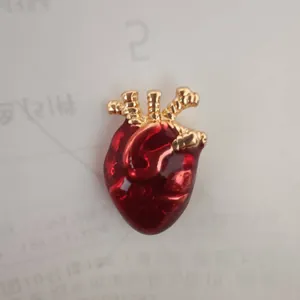 Detailansicht einer realistischen anatomischen Herz-Brosche mit roter Emaille und Gold.