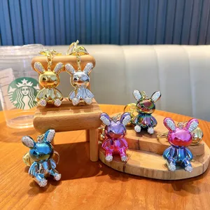 Bunte Glitzer-Hasen-Schlüsselanhänger auf Miniatur-Holzmöbeln stilvoll präsentiert