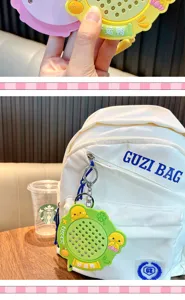 Detalle del llavero de pizarra mágica de pato de la suerte colgado en una mochila blanca