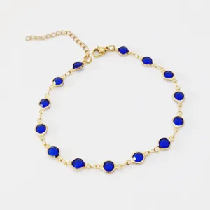 Close-up of golden stainless steel anklet with circular bezel-set blue glass stones