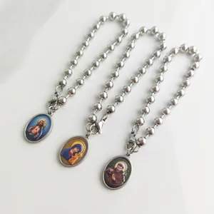 Close-up view of stainless steel ball chain bracelets featuring religious oval pendants.