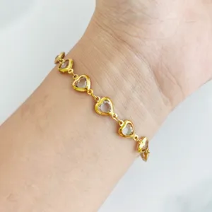 Detailed view of a gold stainless steel heart bracelet with clear crystal charms