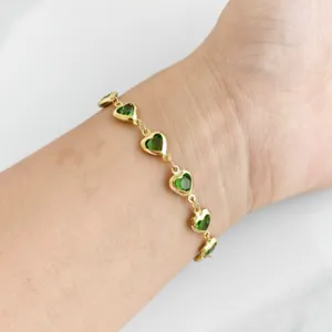 Elegant gold-tone stainless steel bracelet with green heart stones on female wrist