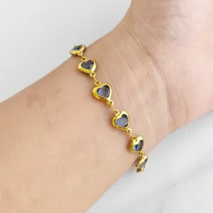 Detailed close-up of a gold stainless steel bracelet featuring vibrant blue heart charms