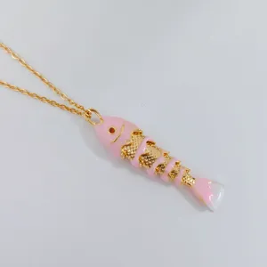 Primer plano de un colgante de pez articulado rosa en una cadena dorada fina.