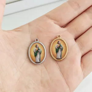Detailed close-up of oval stainless steel religious pendants in gold and silver finishes