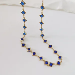 Detail of a stainless steel necklace featuring elegant square blue gemstones in gold